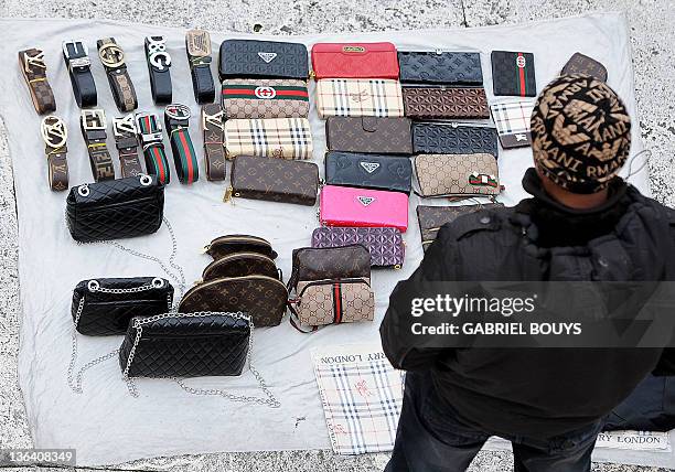 An unidentified vendor display fake designer bags and belts for sale near the Spanish steps in Rome on January 4, 2012. Handbags are displayed on a...