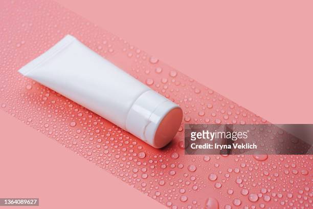 white tube with cosmetic face cream or hand cream, shower gel, shampoo on water drops on a pastel pink background. - hand cream 個照片及圖片檔