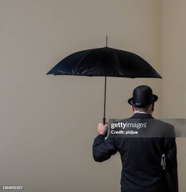 englishman in bowler hat and open black umbrella. - hat and suit stock pictures, royalty-free photos & images