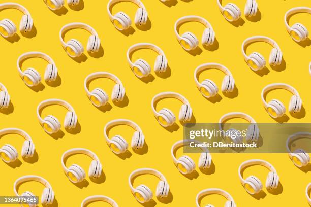 pattern of white wireless headphones with hard shadow on yellow background. concept of music, earphones, radio, podcast, listening and relaxing activity. - headphones isolated foto e immagini stock