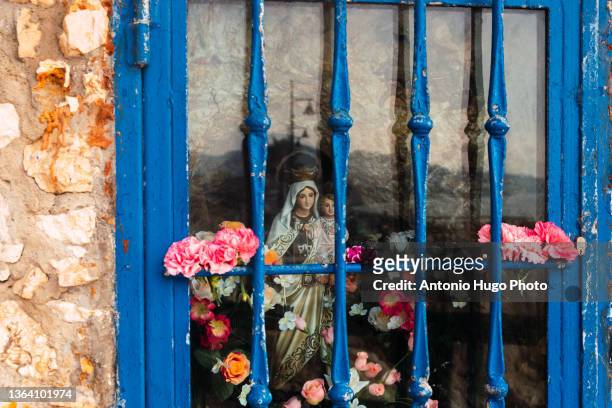 statue of the virgin and jesus christ as seen through a glass. shrine of a virgin on a rock in malaga, spain. - maria sorte - fotografias e filmes do acervo