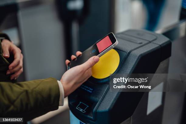 close-up shot of young woman making contactless payment with smartphone at the gate in metro station - credit card terminal stock pictures, royalty-free photos & images