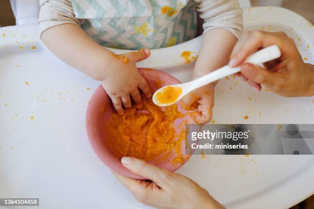frau füttert das baby - porridge stock-fotos und bilder