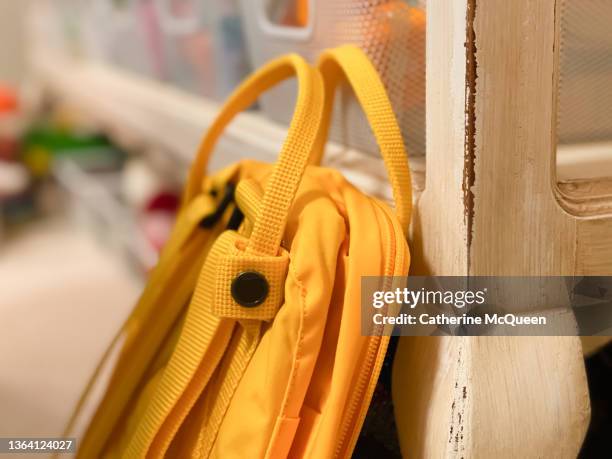 young girl’s bright yellow backpack resting against bookshelf in bedroom - satchel bag stock pictures, royalty-free photos & images