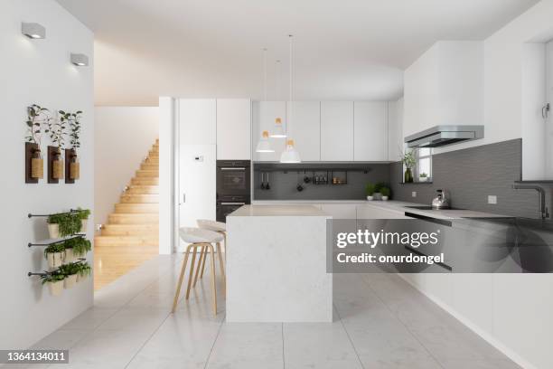 modernes kücheninterieur mit weißen schränken, kücheninsel, hockern und treppe im flur - kitchen tiles stock-fotos und bilder