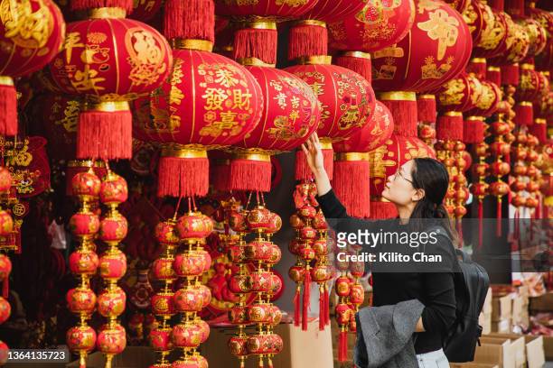 asian woman shopping for chinese new year decorations on the street - woman red lantern stock pictures, royalty-free photos & images