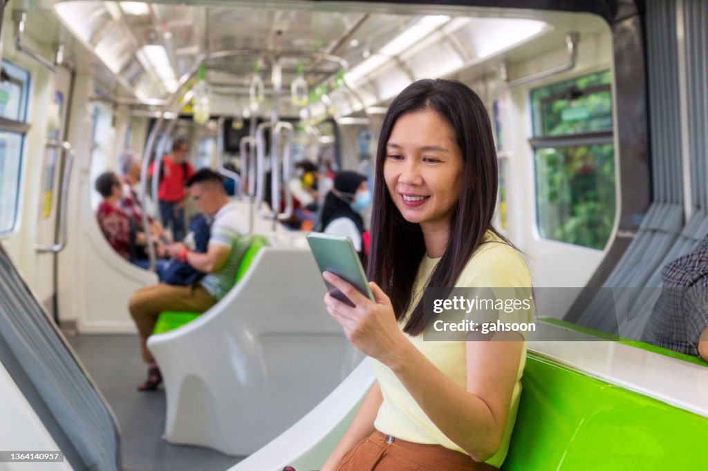 Happy woman traveling by bus and using smart phone