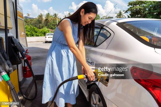 woman refueling her car at a petrol station - refuelling stock pictures, royalty-free photos & images