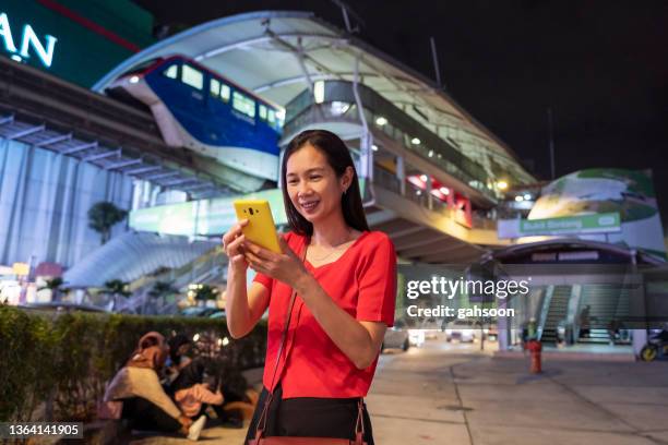 happy woman outdoor using smart phone at night - bukit bintang stock pictures, royalty-free photos & images