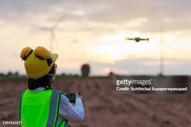 he female engineer using drone for top view inspection wind turbine farm. - drone pilot stock pictures, royalty-free photos & images