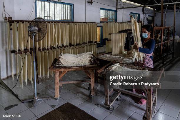 Worker arranges noodles for the drying process at Marga Mulja factory on January 12, 2022 in Surabaya, Indonesia. Longevity white noodles are a...