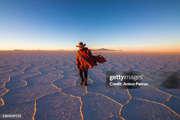 man in poncho at salar de uyuni, aitiplano, bolivia. traveling in bolivia - zuid amerika stockfoto's en -beelden