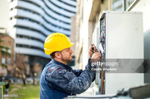 un technicien en climatiseur entretient l’unité de climatisation extérieure et la génératrice à gaz - home repair photos et images de collection