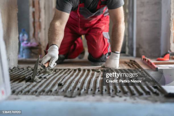 travailleur appliquant de l’adhésif pour carreaux sur le sol - ouvrier maçon photos et images de collection