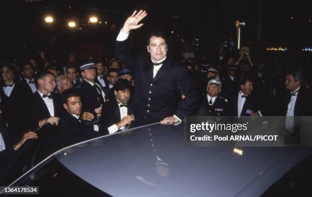 Actor John Travolta waves to crowds while leaning above a car after arriving at the International Film Festival, Cannes, for his film 'Pulp Fiction',...