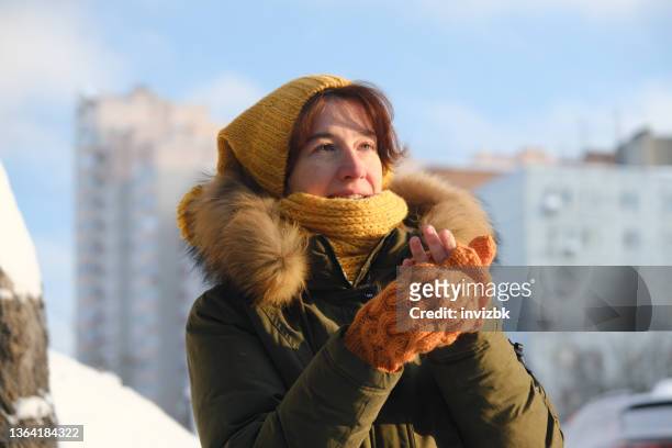 frau zieht an ihren fäustlingen auf der winterstraße - woman hands in mittens stock-fotos und bilder