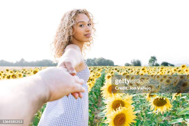 follow me. young woman in plaid dress holding man's hand and leading him to a field of sunflowers. - come and find me stock pictures, royalty-free photos & images