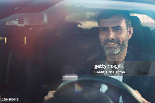 handsome man smiling while driving car - mann 40 bis 50 business auto stock-fotos und bilder