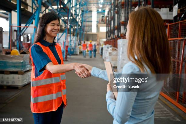 female employee shaking hands with manager in warehouse - navy blue polo shirt stock pictures, royalty-free photos & images