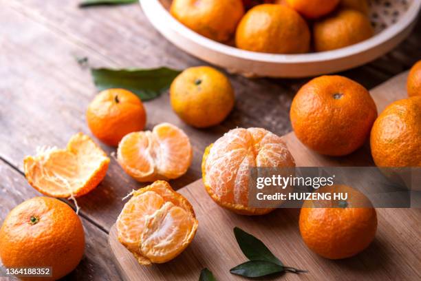 fresh mandarin oranges fruit or tangerines with leaves on a wooden table - mandarijn stockfoto's en -beelden