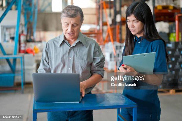 male warehouse manager talking with employee - navy blue polo shirt stock pictures, royalty-free photos & images
