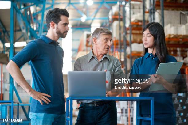 male warehouse manager talking with employees - navy blue polo shirt stock pictures, royalty-free photos & images