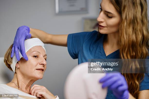 young female doctor talks about beauty treatments during a consultation with a mature woman patient - botoxinjektion bildbanksfoton och bilder