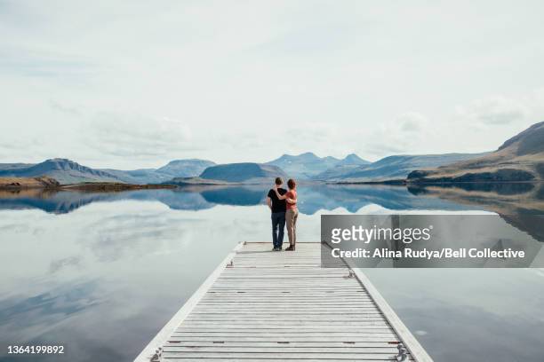 Couple standing on the end of a lake pier