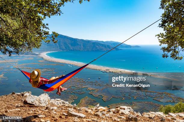 the woman lying in the hammock is looking at the beach with pleasure. - aegean islands stockfoto's en -beelden