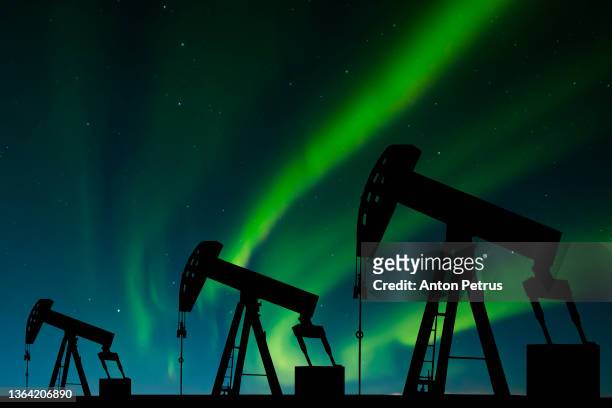 oil pump on the northern lights background. oil production in the far north - arctic oil stock-fotos und bilder