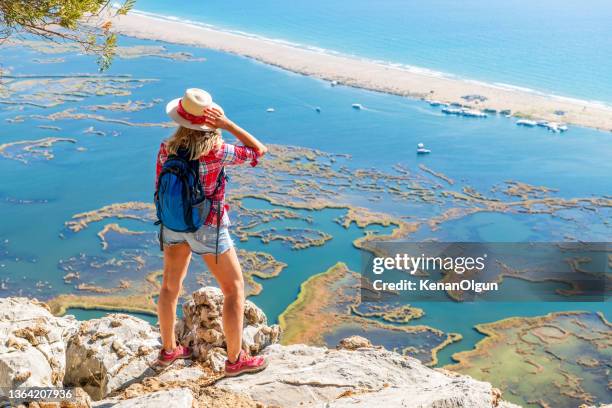 hiker woman looking down at the beach. - turtle beach stock pictures, royalty-free photos & images