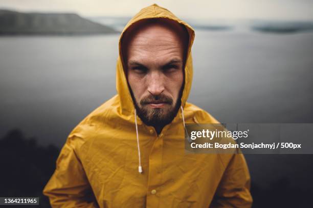 brutal bearded man in yellow raincoat - rain coat stock pictures, royalty-free photos & images