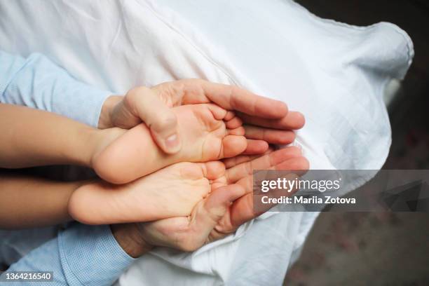 a parent holds his son's legs - grande tablée photos et images de collection