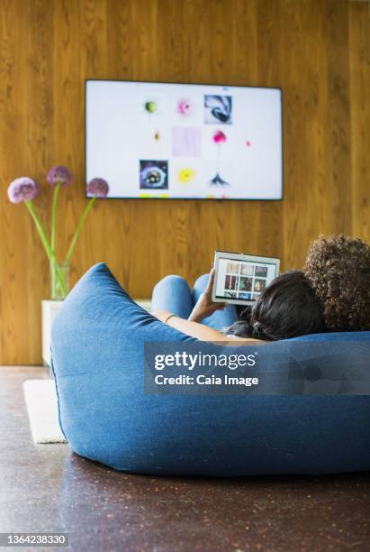 young couple streaming photos from digital tablet to tv - young couple watching tv stock pictures, royalty-free photos & images