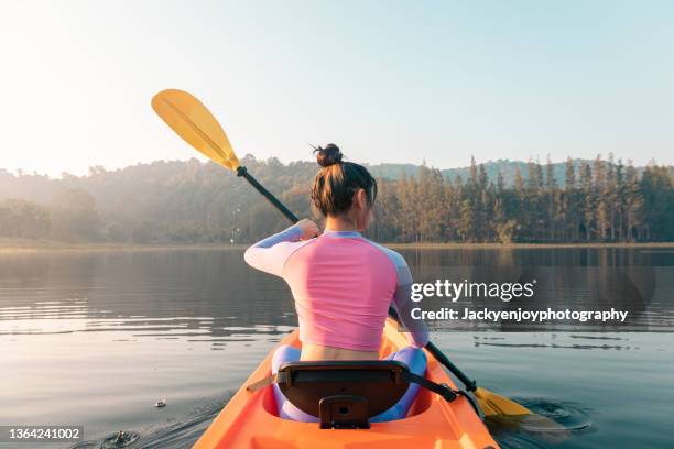 woman paddling into sunset on a lake in a kayak