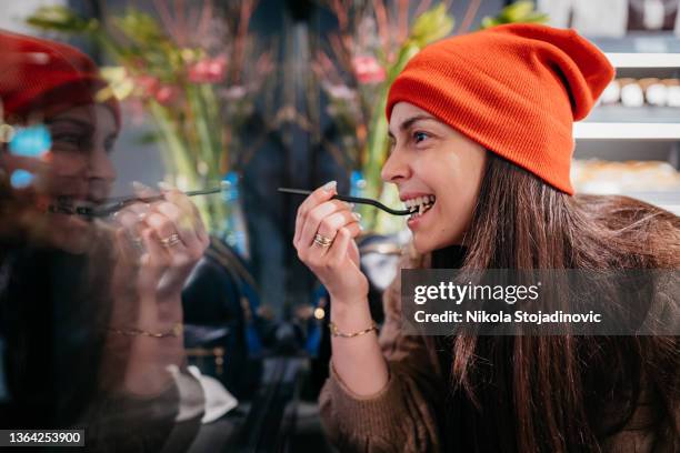 the woman enjoys the cakes in the bakery - cake case stock pictures, royalty-free photos & images