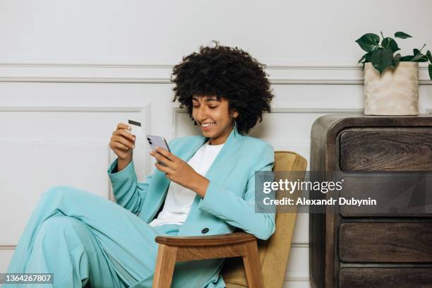 happy african woman with mobile phone and credit card shopping or taking out a loan online. business and bank concept - buying photos et images de collection