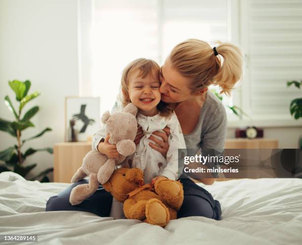 tiempo de unión: mamá y su hija jugando con juguetes de peluche en la cama por la mañana - mother and child fotografías e imágenes de stock