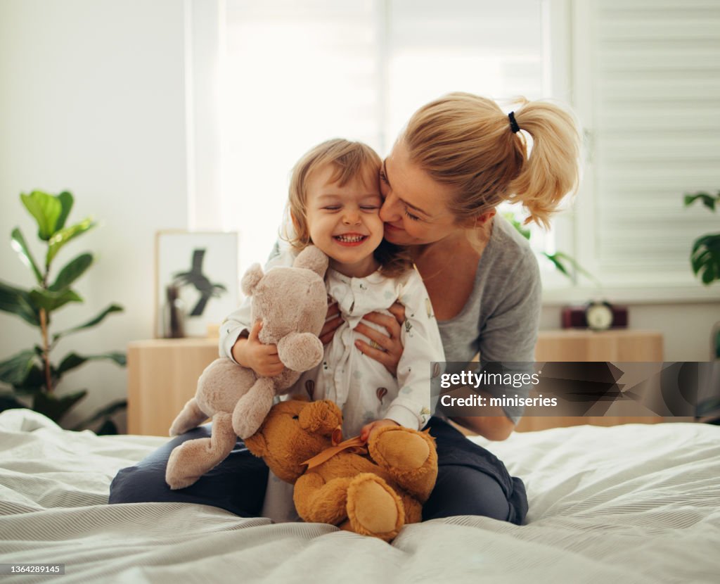 Tempo di legame: mamma e sua figlia giocano con giocattoli di peluche sul letto al mattino
