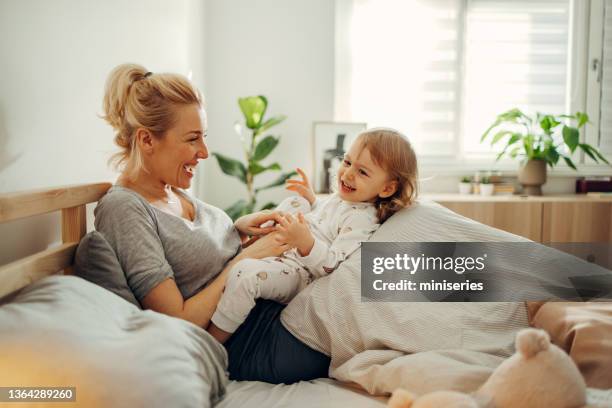 happy mother and daughter cuddling in bed in the morning - tickling stock pictures, royalty-free photos & images