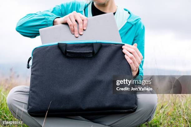 a woman putting her laptop in its case - maletín para portátil fotografías e imágenes de stock