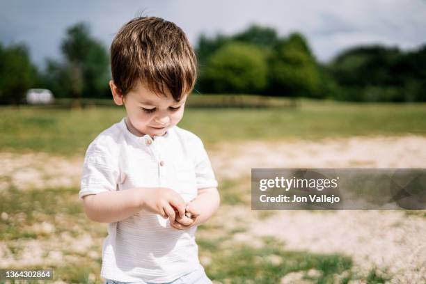 little boy playing with stones holding them in his hands - stone hand stock-fotos und bilder