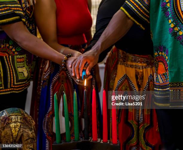 celebración de kwanzaa, primer plano de la familia encendiendo la vela kinara en espíritu de unidad - kwanzaa fotografías e imágenes de stock