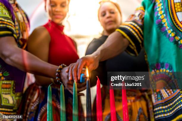 celebração kwanzaa, família afro-americana acendendo a vela kinara juntos em casa em espírito de unidade - kinara - fotografias e filmes do acervo