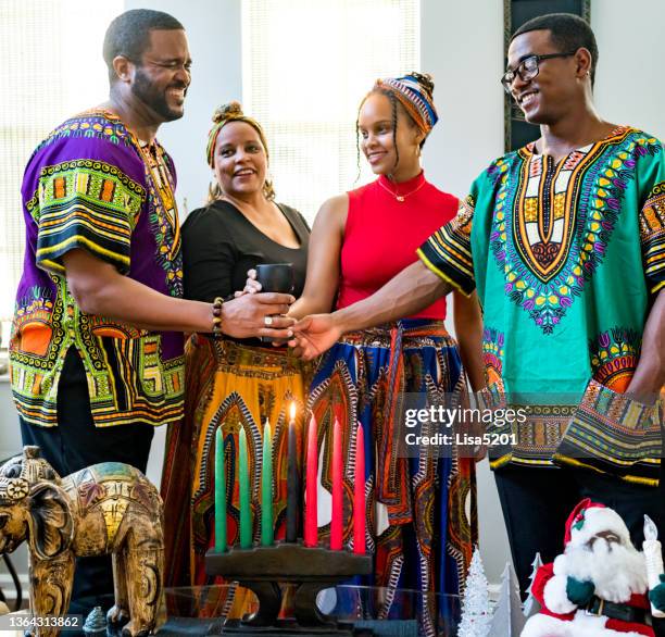 kwanzaa celebration, african american family holding the unity cup together at home with kinara - kwanzaa celebration stock pictures, royalty-free photos & images