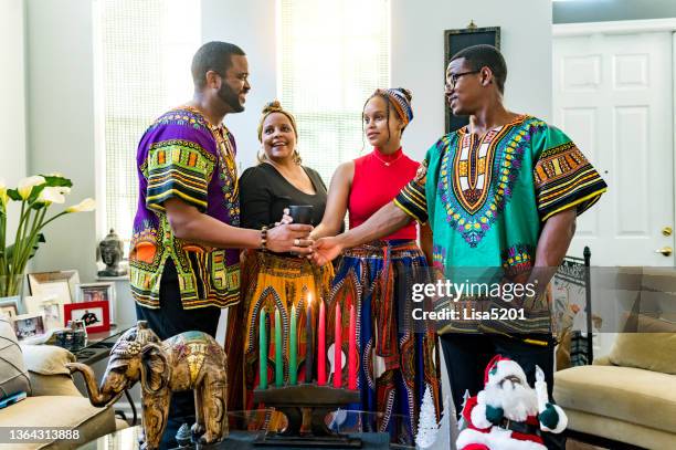 kwanzaa celebration, african american family holding the unity cup together at home with kinara - kwanzaa stock pictures, royalty-free photos & images