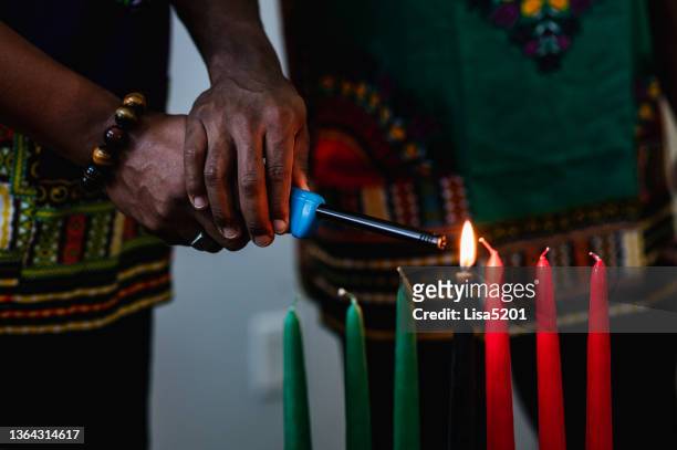 kwanzaa celebration, close up two people lighting the kinara candle in spirit of unity - kwanzaa stock pictures, royalty-free photos & images