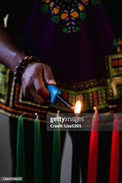 kwanzaa celebration, close up lighting the kinara candle - kwanzaa stock pictures, royalty-free photos & images