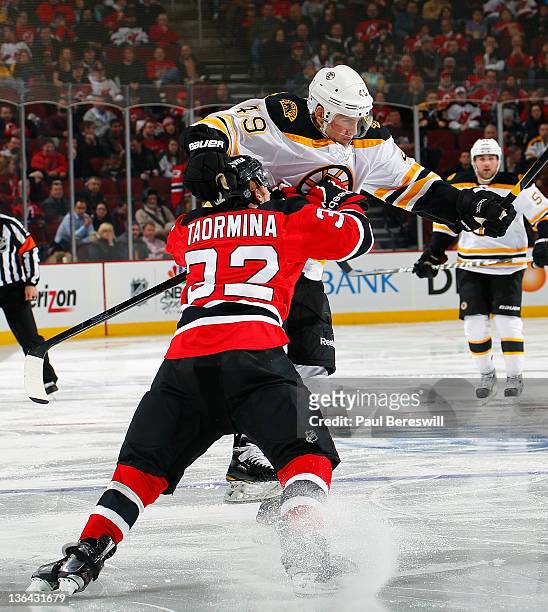 Rich Peverley of the Boston Bruins is knocked off his feet on this check by Matt Taormina of the New Jersey Devils during the third period of an NHL...