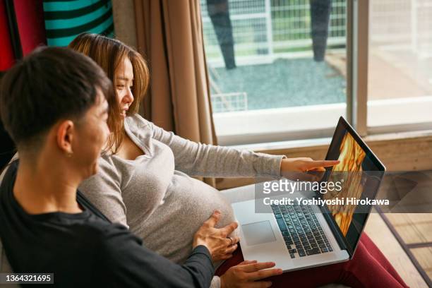 surfer couple looking at ultrasound picture of foetation inside his wife on laptop - couple before marriage stock-fotos und bilder